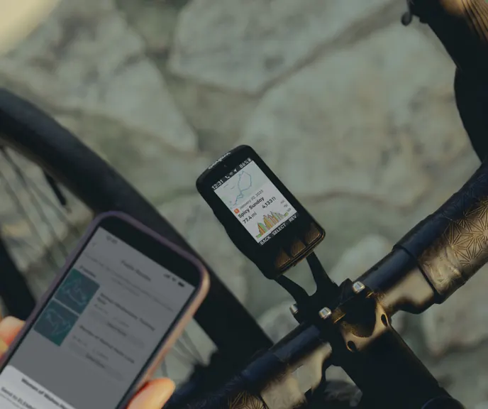 An ELEMNT bike computer on an out-front bar mount, a rider checking the Wahoo app